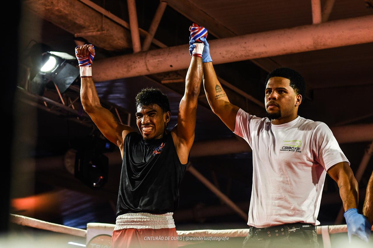 Atleta de boxe com os braços erguidos no ringue
